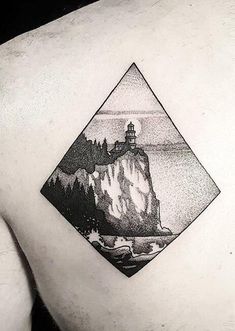 a black and white photo of a man's back with a lighthouse on it