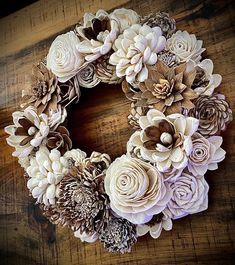 a wreath made out of paper flowers sitting on top of a wooden table