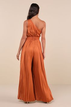 Feel extra eye-catching with each step you take in the Lulus Exquisite Always Rust Orange Pleated Satin One-Shoulder Jumpsuit! Sleek, pleated woven satin shapes this luxe jumpsuit that features a blousy bodice with ruching along the side, a one-shoulder neckline, and a single wide strap. A twisted, pleated band accents the fitted waist, all atop breezy, wide pant legs that fall to full-length hems. Hidden side zipper/clasp. Fit: This garment fits true to size. Length: Floor length. Size medium m Formal Jumpsuit Prom, Vibrant Bridesmaids, Dressy Casual Wedding, Wedding Guest Jumpsuit, Wedding Jumpsuits, Jumpsuit Wedding Guest, Jumpsuit Prom, Wedding Guest Romper, Jumpsuit Wedding