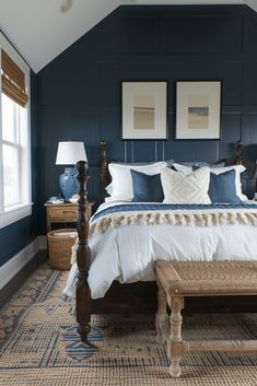 a bedroom with blue walls, white bedding and two framed pictures on the wall