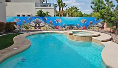 an outdoor swimming pool with fish and corals painted on the wall next to it