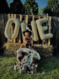 a young boy is sitting in front of the sign for his farm themed birthday party