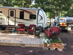 an rv is parked in the woods next to a deck with chairs and couches