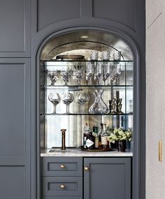 a gray cabinet with wine glasses and bottles on it's glass front doors is shown