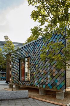 a small building made out of different colored glass tiles on the side of a street