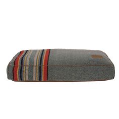 a dog bed that is made out of gray fabric with red, yellow and blue stripes