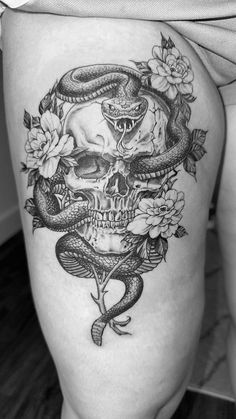 a woman's thigh with a snake and skull tattoo on it