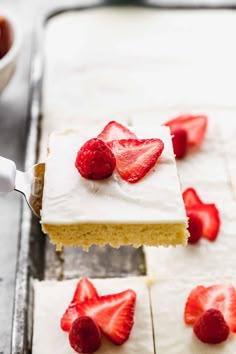 a piece of cake with white frosting and strawberries on top