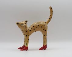 a ceramic figurine of a cat with black dots on it's body