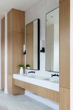 a bathroom with two sinks, mirrors and vases on the counter top next to each other