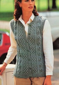 a woman wearing a sweater vest and holding a skateboard