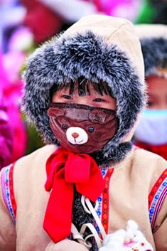 a person wearing a mask with a red bow around his neck and holding something in their hand