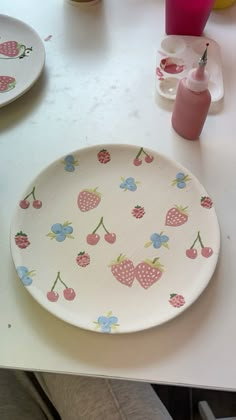 a white table topped with a plate covered in strawberrys and polka dot designs on it