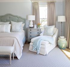 a bed room with a neatly made bed next to a chair and a dresser in front of a window