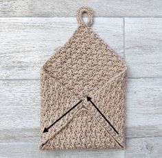 a crocheted pot holder with an arrow on the side and two black arrows pointing towards it