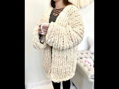 a woman standing in front of a couch holding a cup