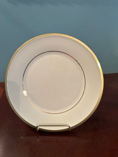 a white and gold plate sitting on top of a wooden table next to a blue wall