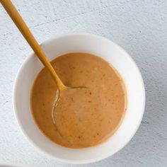 a white bowl filled with sauce and a wooden spoon