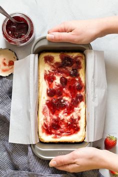 someone is holding a pan with food in it on the table next to some strawberries