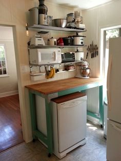 a kitchen area with a table, shelves and appliances