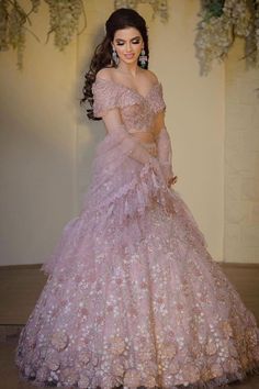 a woman in a pink gown standing on the floor with her hands behind her back