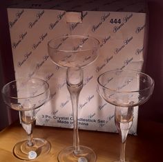 three wine glasses sitting on top of a wooden table