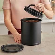 a woman is pouring coffee into a black container