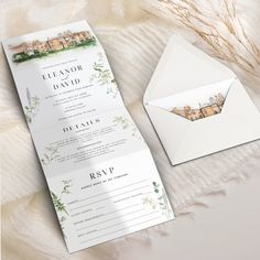 the wedding stationery is laid out next to an open envelope and some papers on a white blanket