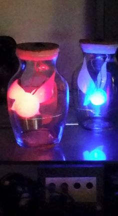 three lit up vases sitting on top of a table