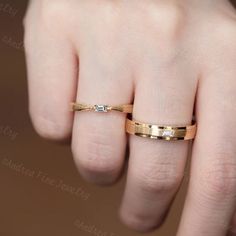 a woman's hand with a gold wedding band and two diamond rings on it