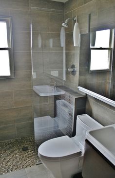 a white toilet sitting in a bathroom next to a sink and shower head mounted faucet