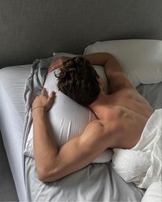 a shirtless man laying in bed with his back turned to the side and sleeping