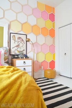 a bedroom with hexagonal wallpaper and yellow bedding, black and white striped rug