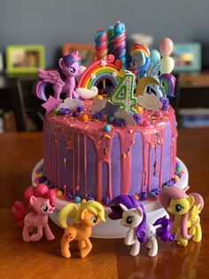 a birthday cake with little pony figurines around it on top of a table