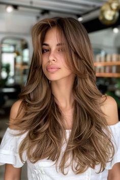 Woman with long, layered brown hair in a modern salon. Hair Balayage For Brown Skin, Honey Brown Caramel Hair, Bronde Balayage Dimension, Chestnut Bronde Balayage, Caramel Hair With Dark Roots, Honey Brown Hair No Highlights, Brown Eyes Best Hair Color, Caramel Hair On Tan Skin, Toffee Hair Color Brown Highlights