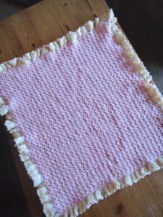 a pink crocheted blanket sitting on top of a wooden table