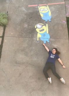 a woman standing in front of a chalk drawing of two cartoon characters on the sidewalk