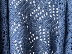 a blue knitted shawl with white squares on it