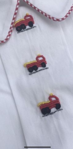 three embroidered cars on a white shirt with red and yellow trim around the collars