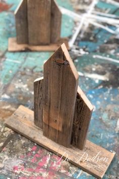 two wooden houses sitting on top of a piece of wood in front of some paint