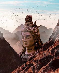 there is a statue on top of a mountain with birds in the sky above it