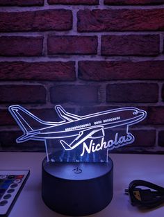 an airplane shaped neon sign sitting on top of a table next to a remote control