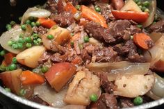 a pot filled with meat and vegetables on top of a stove next to broccoli