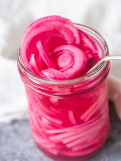 a jar filled with red liquid sitting on top of a white table next to a napkin