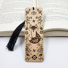 a wooden bookmark with an image of a fox on it and tassels