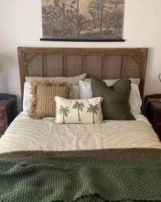 a bed with pillows and blankets on top of it next to a painting above the headboard