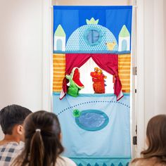 a group of children sitting in front of a door with a puppet on it's side