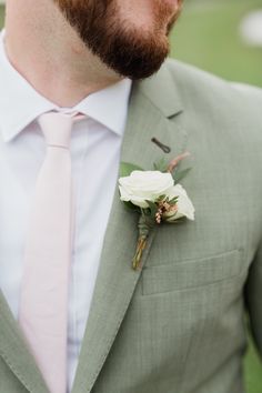 a man in a suit with a pink tie and white flower on his lapel