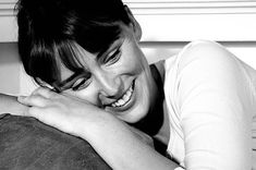 black and white photograph of a woman smiling with her arm around the back of a pillow