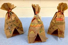 three brown bags sitting on top of a blue table covered in paper mache art